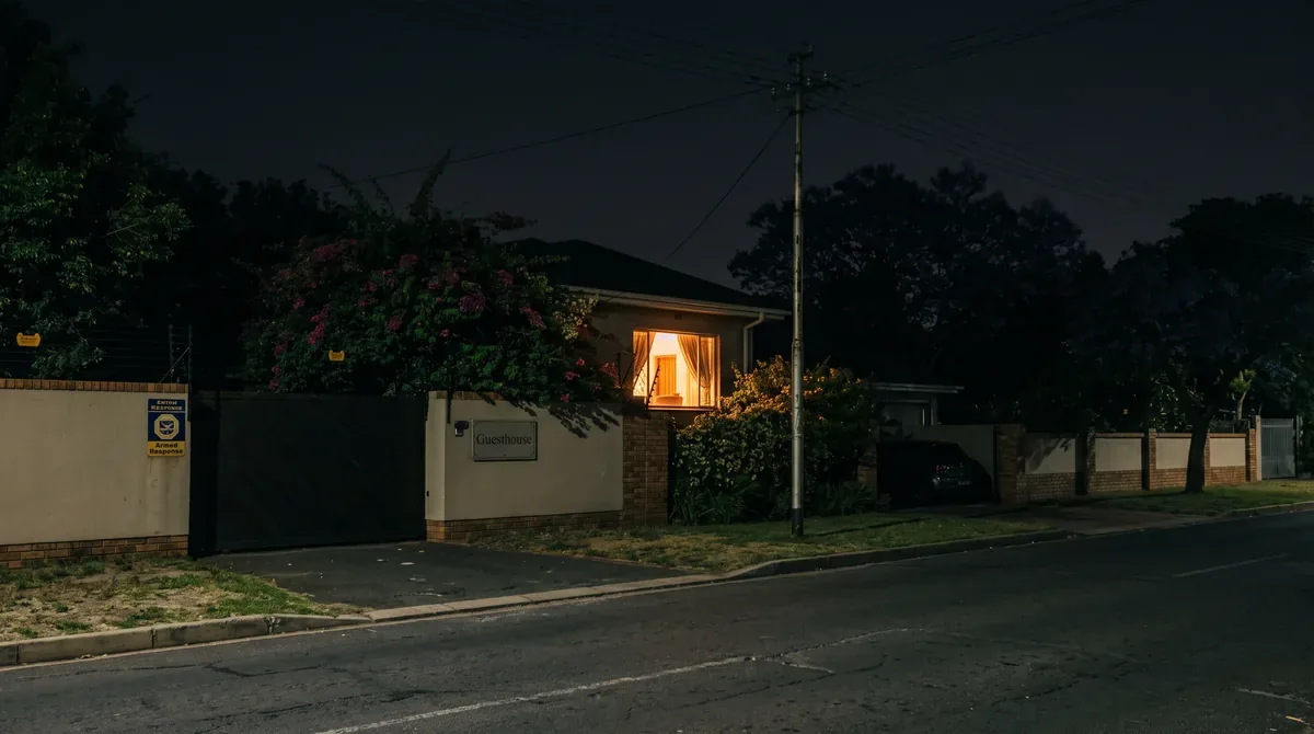 A suburban guesthouse at night with one lit window